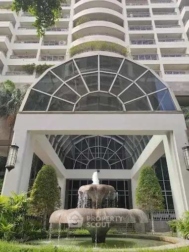 Elegant building entrance with grand fountain and lush greenery