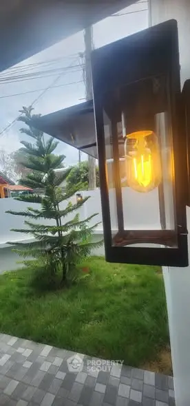 Modern outdoor light fixture illuminating a lush garden with paved pathway.
