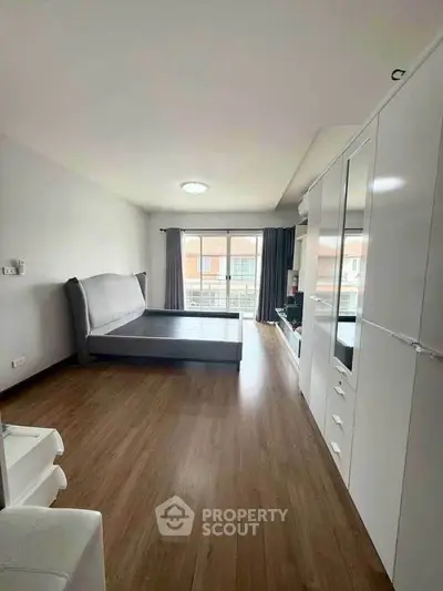 Spacious bedroom with modern furnishings and large window for natural light.