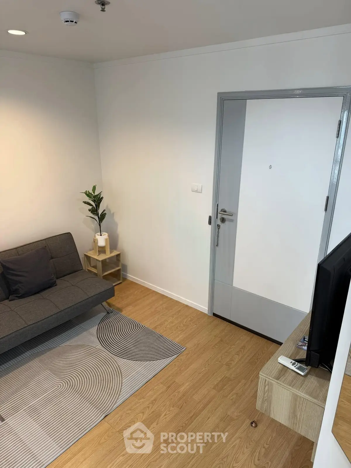 Modern living room with sleek furniture and stylish decor, featuring a cozy sofa and a minimalist TV setup.