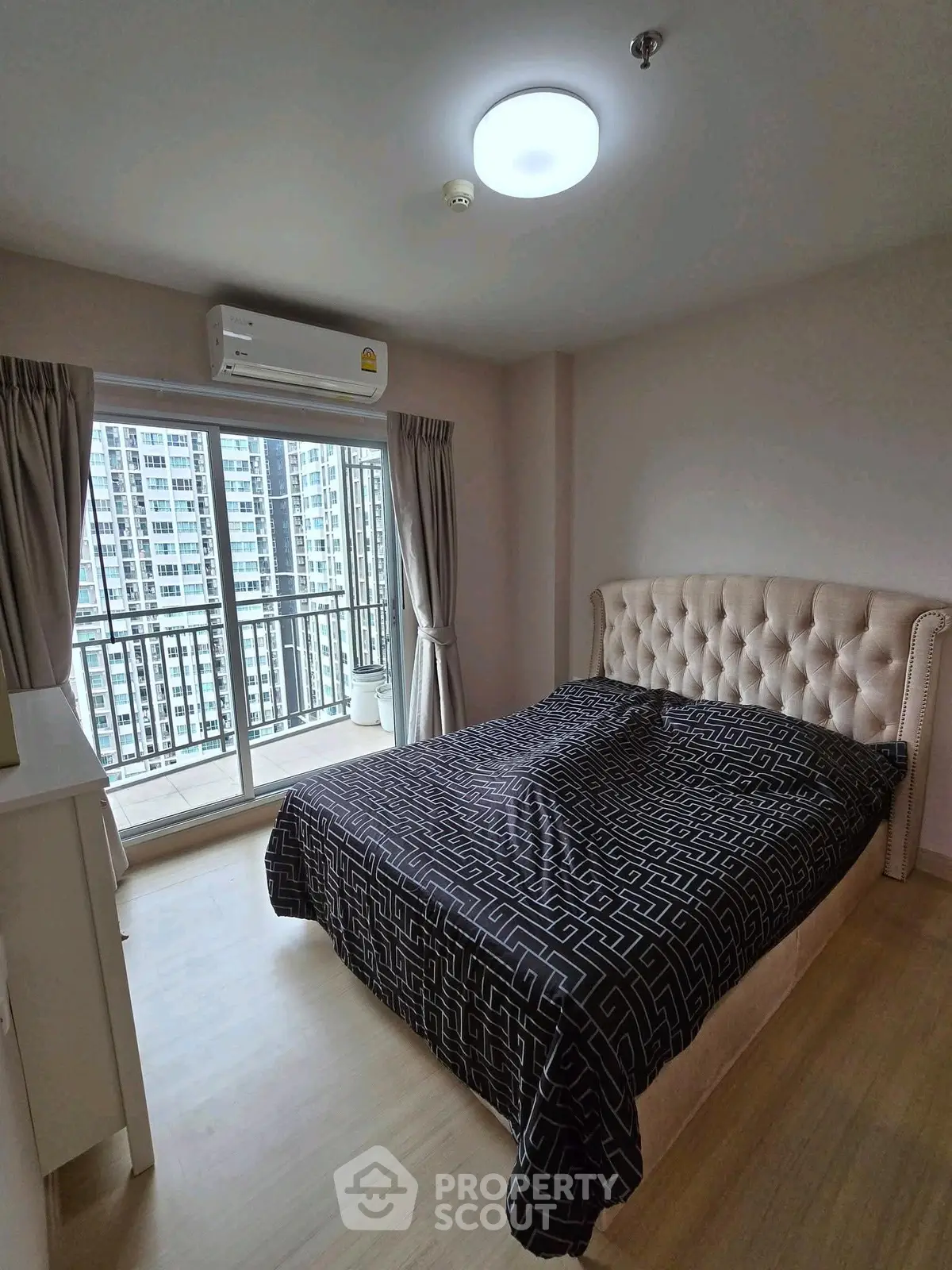 Modern bedroom with balcony view in high-rise apartment, featuring elegant bed and natural light.