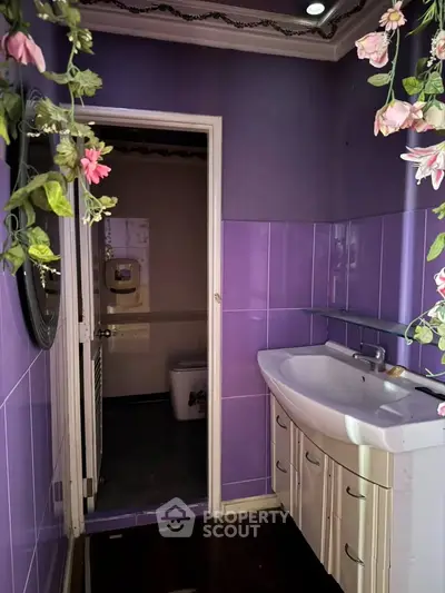 Charming purple-tiled bathroom with elegant sink and floral decor