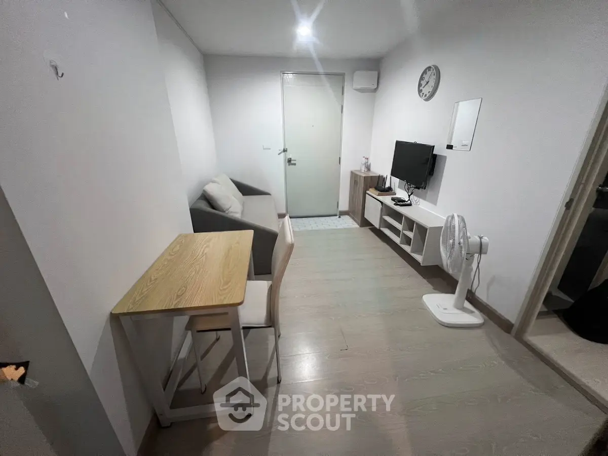 Cozy living room with modern decor, featuring a sofa, TV, and dining table in a compact apartment.