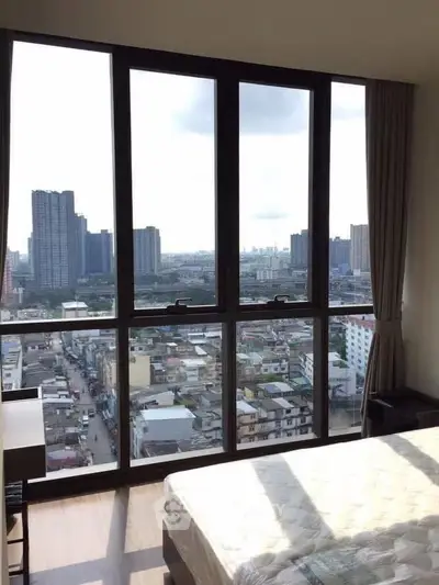 Stunning high-rise bedroom with panoramic city view and large windows.