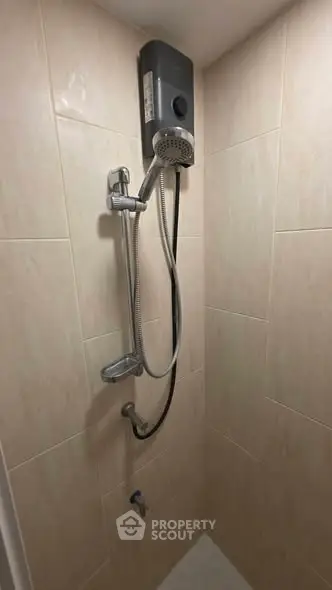 Compact bathroom shower area with modern water heater and tiled walls.