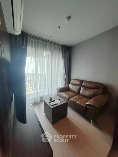 Cozy living room with leather sofa and large window offering natural light.
