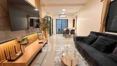 Modern living room with sleek furniture and stylish decor, featuring a large TV and elegant dining area.