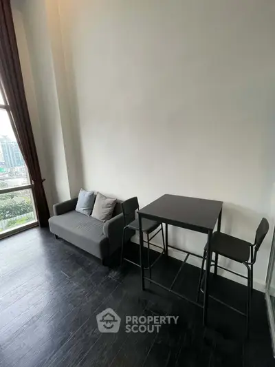 Modern living room with high ceiling, dark wood flooring, and city view window.