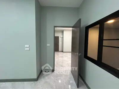 Modern interior with sleek design, featuring a partially open door and glossy tiled flooring.