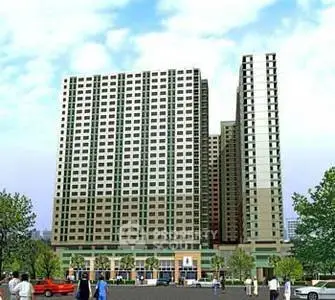 Modern high-rise residential building with urban surroundings and clear blue sky.