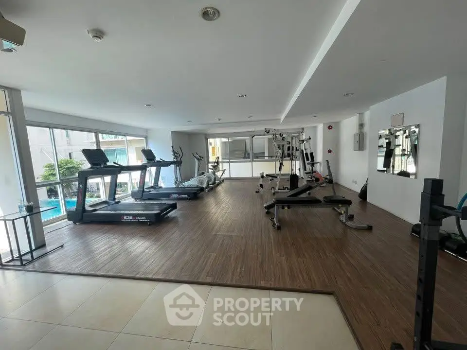 Spacious modern gym with state-of-the-art equipment and pool view, perfect for fitness enthusiasts.