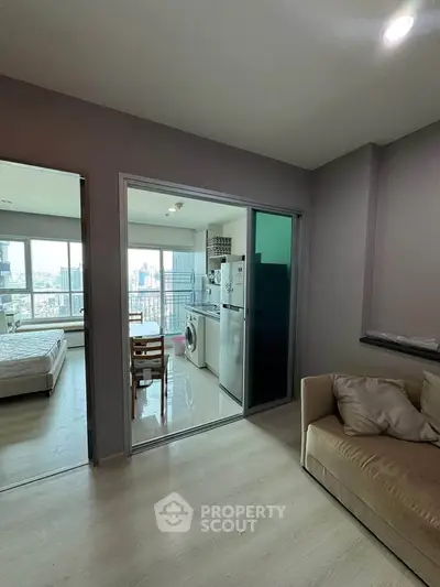 Modern apartment interior with open kitchen and city view, featuring a cozy living area and bright bedroom.