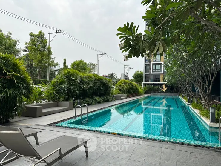 Luxurious condominium pool area with lush greenery and modern design, perfect for relaxation and leisure.