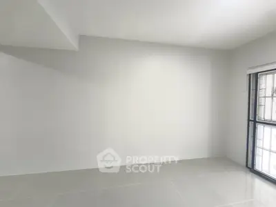 Spacious empty room with large window and tiled floor, perfect for customization.
