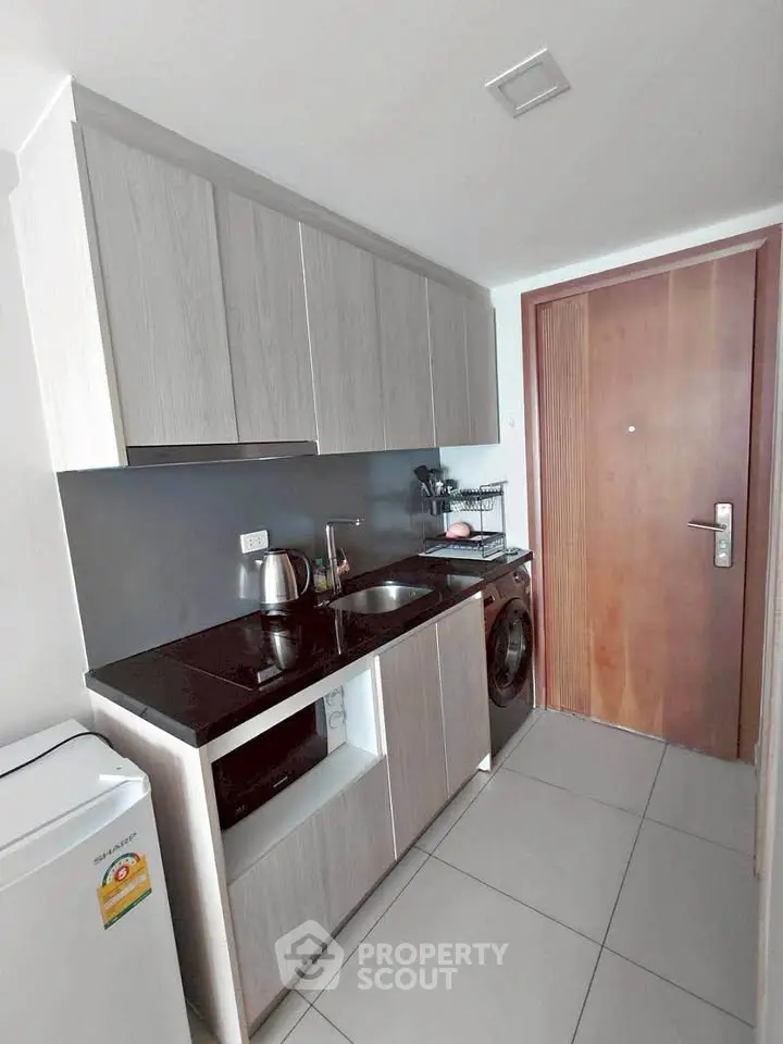 Modern compact kitchen with sleek cabinetry and integrated appliances in a stylish apartment.
