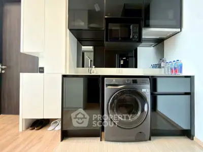 Modern kitchen with built-in appliances and washing machine in sleek design.