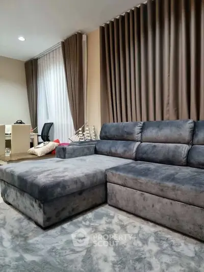 Spacious living room with plush gray sectional sofa and elegant floor-to-ceiling curtains.