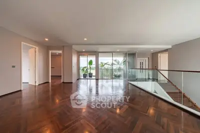 Spacious modern living room with hardwood floors and large windows offering natural light.