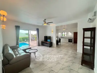 Spacious open-plan living room with pool view and modern kitchen in a stylish home.