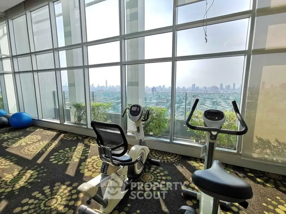 Luxurious gym with panoramic city views and modern exercise equipment in a high-rise building.