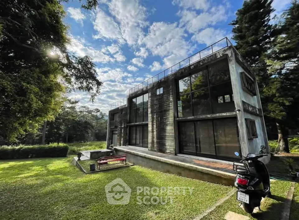 Modern industrial-style house with large windows and lush green surroundings