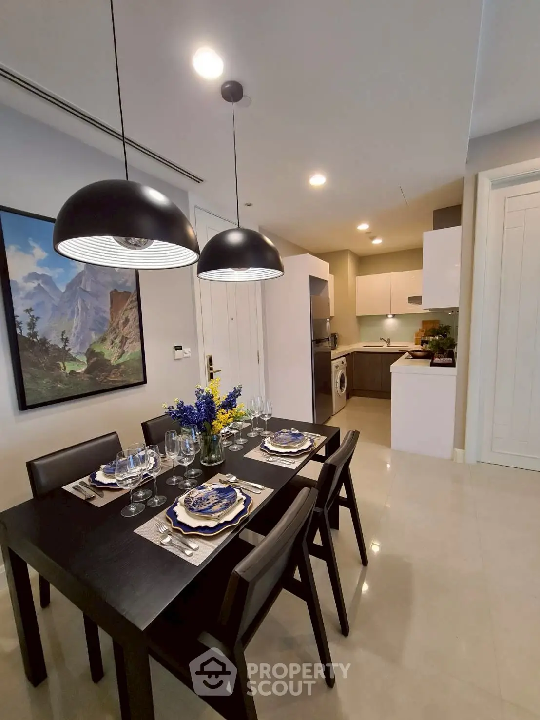 Modern dining area with elegant table setting and view into a sleek kitchen with appliances.