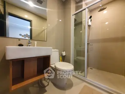Modern bathroom with sleek shower and stylish sink in contemporary apartment.