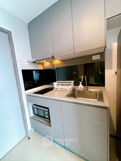 Modern compact kitchen with sleek cabinetry and built-in appliances in a stylish apartment.
