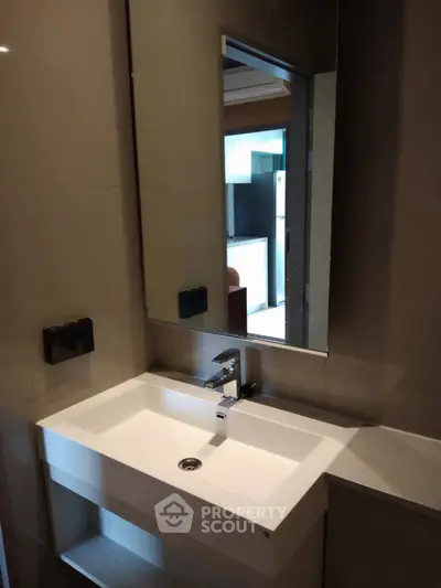 Modern bathroom with sleek sink and large mirror in contemporary apartment.