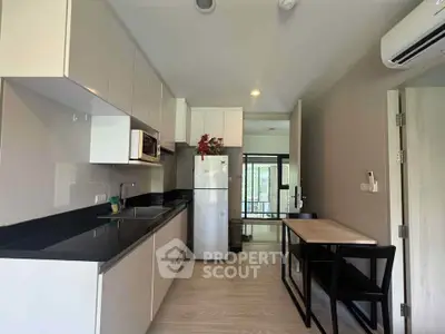 Modern kitchen with sleek cabinetry and dining area in a stylish apartment.