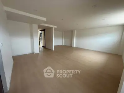 Spacious empty room with wooden flooring and natural light, ideal for customization.