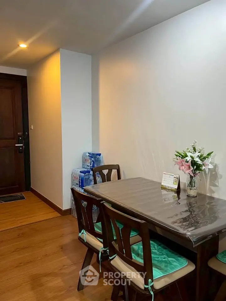 Cozy dining area with wooden table and chairs, accented by fresh flowers and soft lighting.