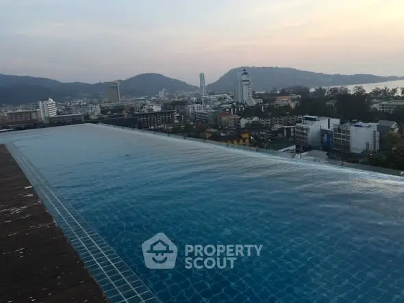 Stunning rooftop infinity pool with panoramic city and mountain views at sunset.