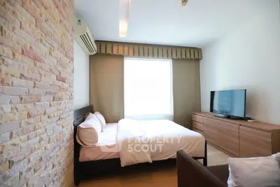 Modern bedroom with stylish brick accent wall and large window for natural light.