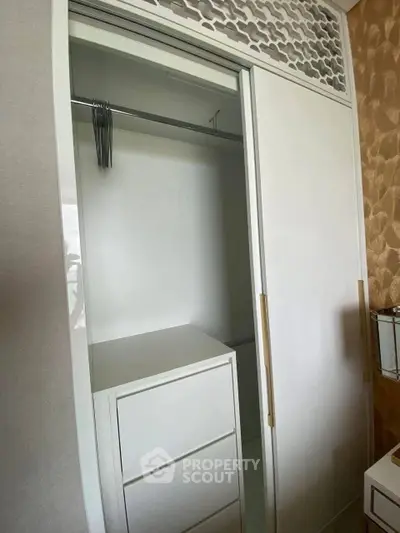 Modern white wardrobe with sliding doors and built-in drawers in a stylish bedroom.