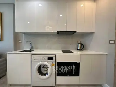 Modern kitchen with sleek white cabinets, built-in appliances, and washing machine.