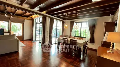 Spacious living room with wooden floors and large windows in a charming home.