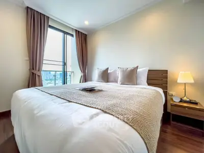 Elegant bedroom with city view, featuring cozy bedding and modern decor.