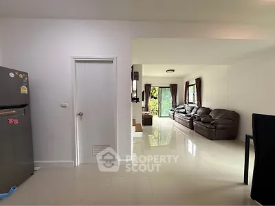 Spacious living room with leather sofas and garden view, adjacent to modern kitchen.