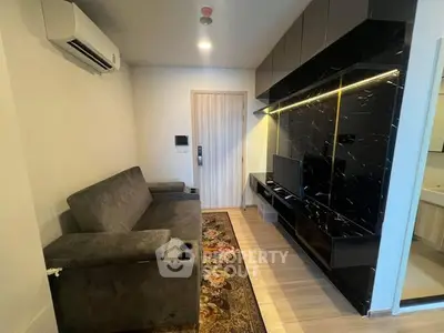 Modern living room with sleek black entertainment unit and cozy gray sofa.