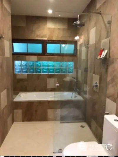 Luxurious bathroom with glass shower and bathtub, featuring modern tile design and ambient lighting.