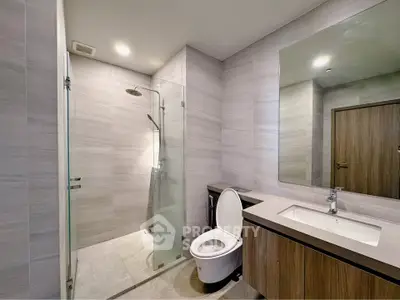 Modern bathroom with glass shower and sleek vanity in contemporary apartment.