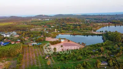 Scenic aerial view of lush green landscape with lake and distant hills, perfect for real estate development.
