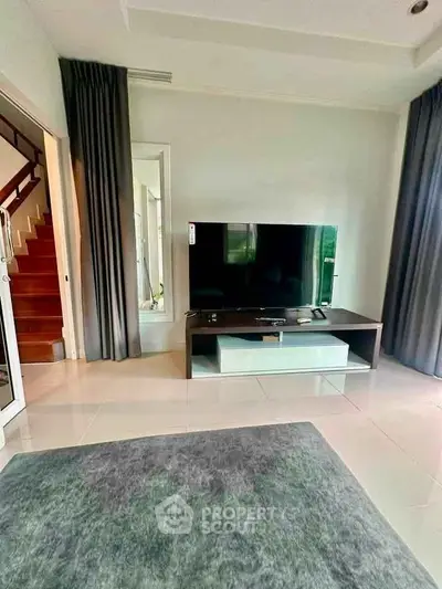 Modern living room with sleek TV setup and elegant curtains, perfect for cozy family gatherings.