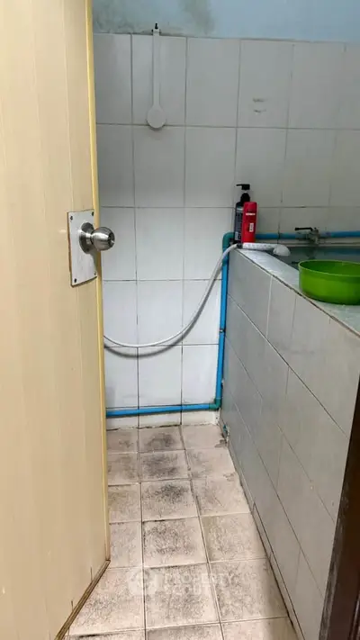Compact bathroom with tiled walls and floor, featuring a bathtub and basic fixtures.