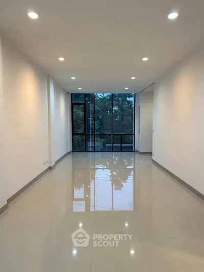 Spacious modern living room with large windows and glossy tiled floor