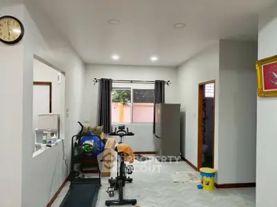 Spacious living area with exercise equipment and modern decor, featuring a large window for natural light.