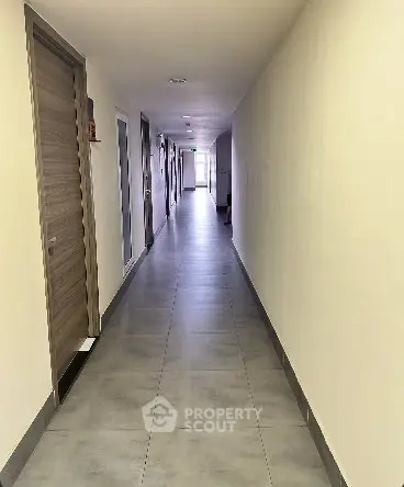 Spacious corridor in modern residential building with sleek tile flooring.