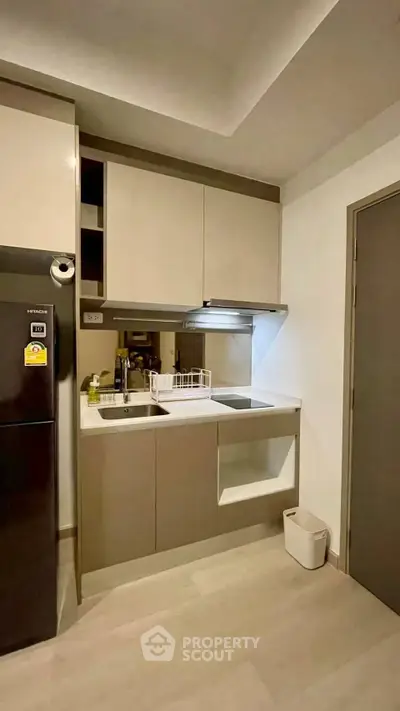 Modern compact kitchen with sleek cabinetry and stainless steel appliances in a stylish apartment.