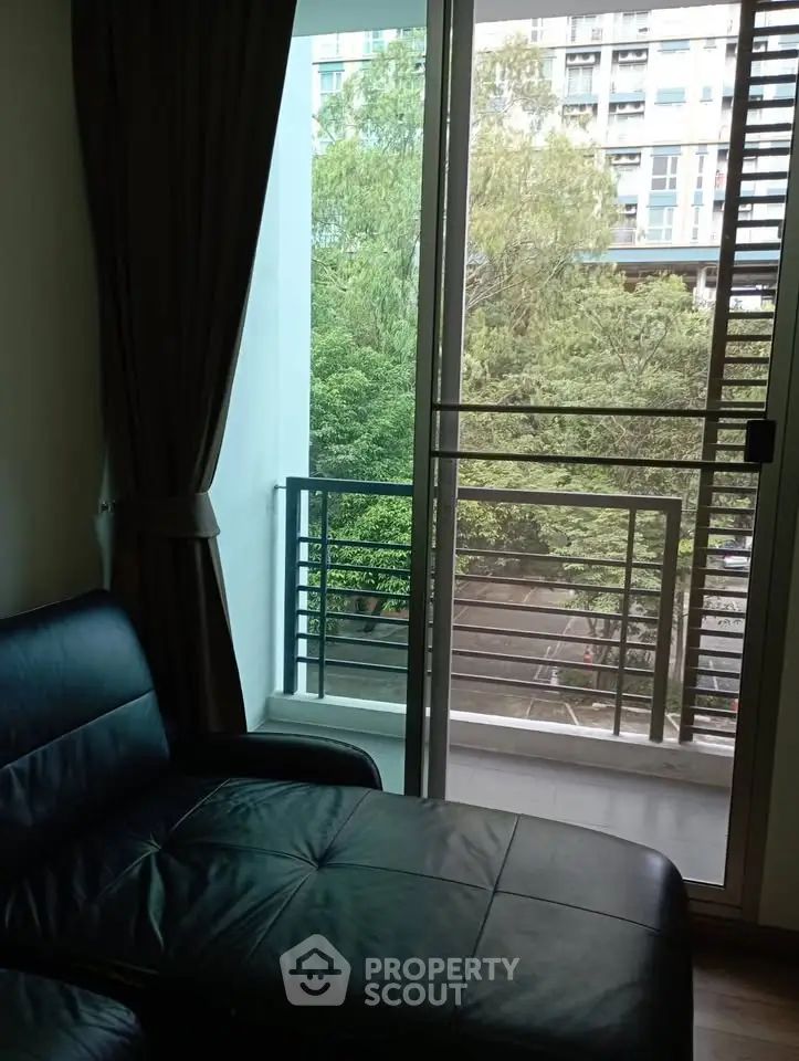 Cozy living room with balcony view and lush greenery